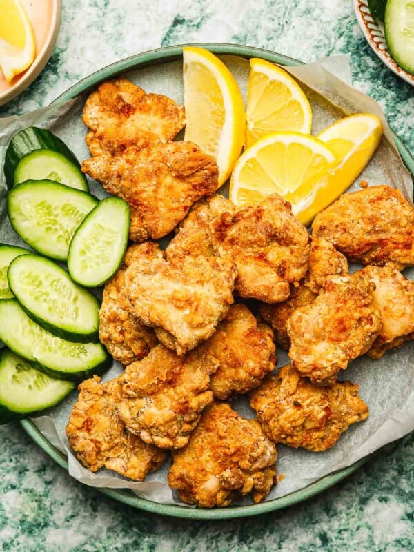 Feature image shows a plate of crispy Japanese fried chicken made in an air fryer and serve with lemon and cucumber slices on the side.