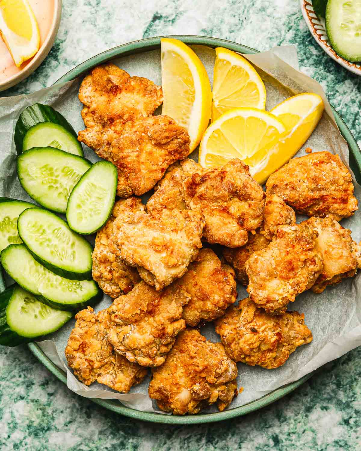 Feature image shows a plate of crispy Japanese fried chicken made in an air fryer and serve with lemon and cucumber slices on the side.