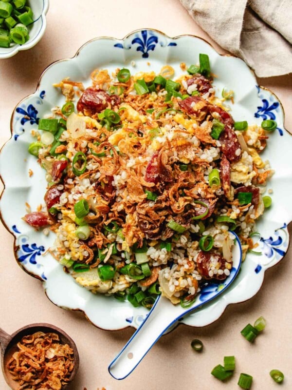 Overhead feature image shows a plate of golden crisp fried rice with Chinese sausage served in a blue white color plate.