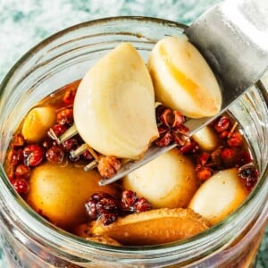 Recipe image shows pickled garlic soaked in a Sichuan ginger peppercorn brine.