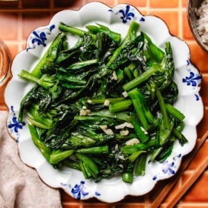 A recipe image of stir fried yu choy sum with garlic bits on top.