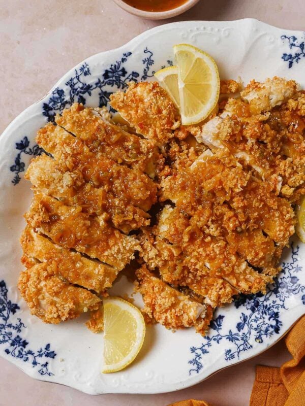 Feature image shows a plate of crispy chinese lemon chicken drizzled with lemon sauce, served over a big blue white color plate.