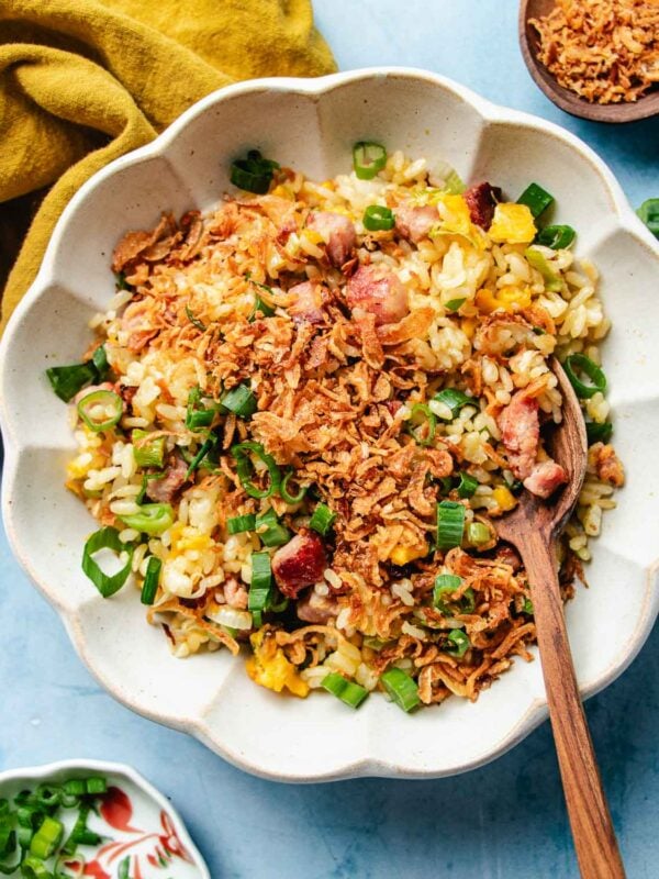 Feature image shows a plate of crisp and yellow golden fried rice, topped with crispy shallots, scallions, served over a white color plate.