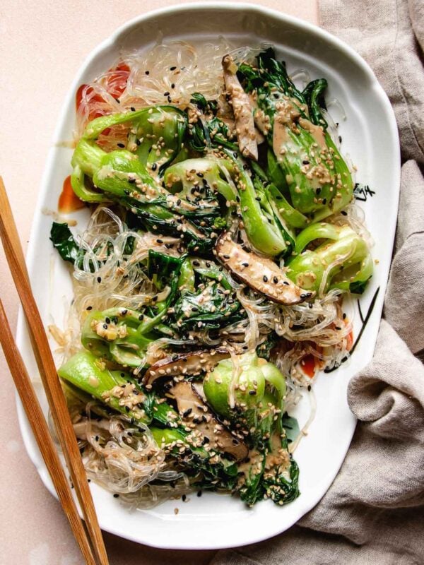 Feature image shows a plate of silky and smooth kelp noodles tossed with sauteed bok choy, shiitake, in a creamy sesame dressing.