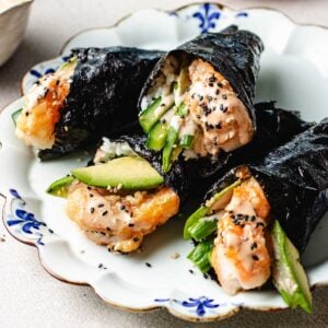 Recipe image shows shrimp sushi hand rolls wrapped in nori sheets with avocado, cucumber, sushi rice, and drizzled with bang bang sauce.