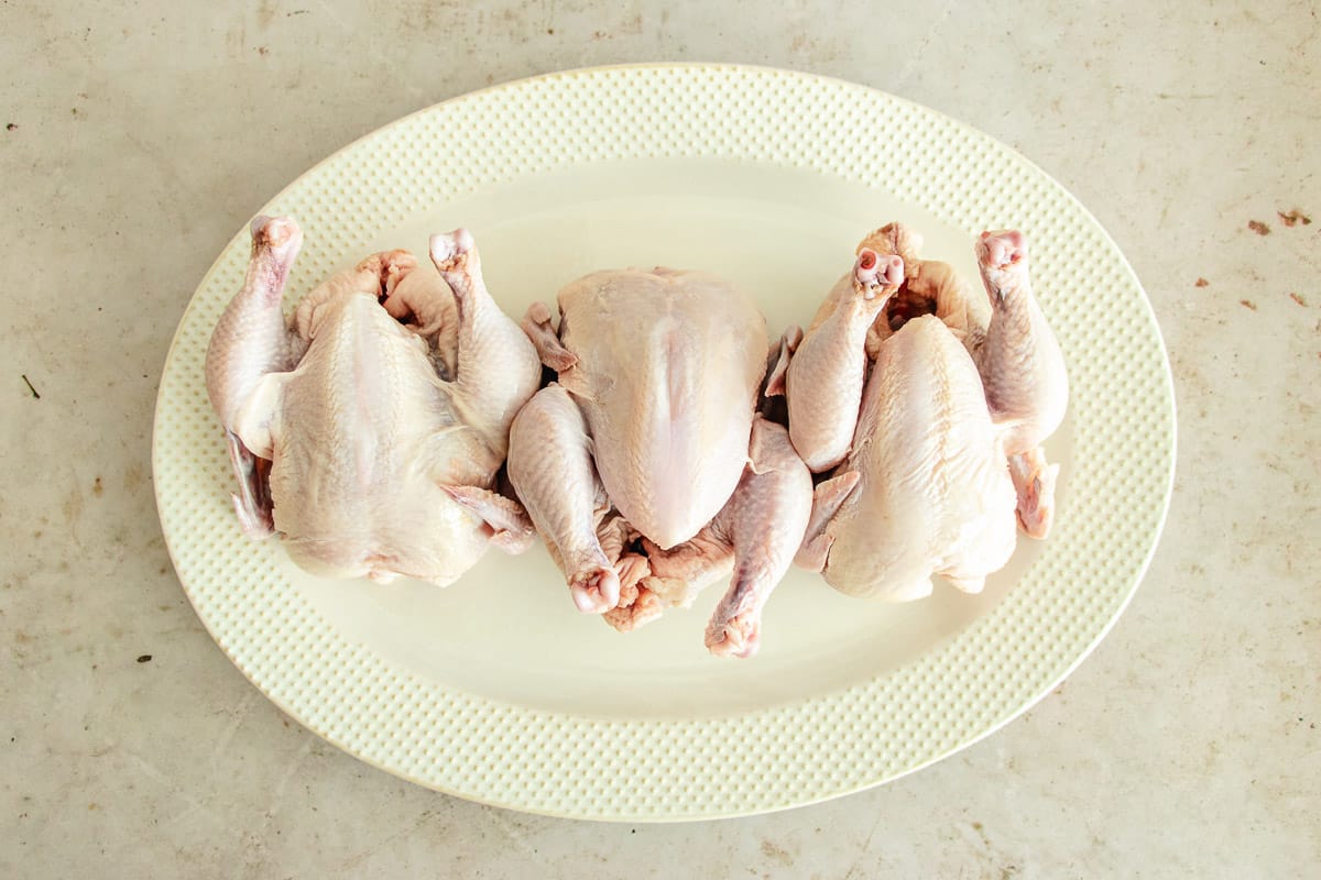 Raw cornish hens on a plate, ready to be seasoned and transformed into delicious roasted Cornish hens.