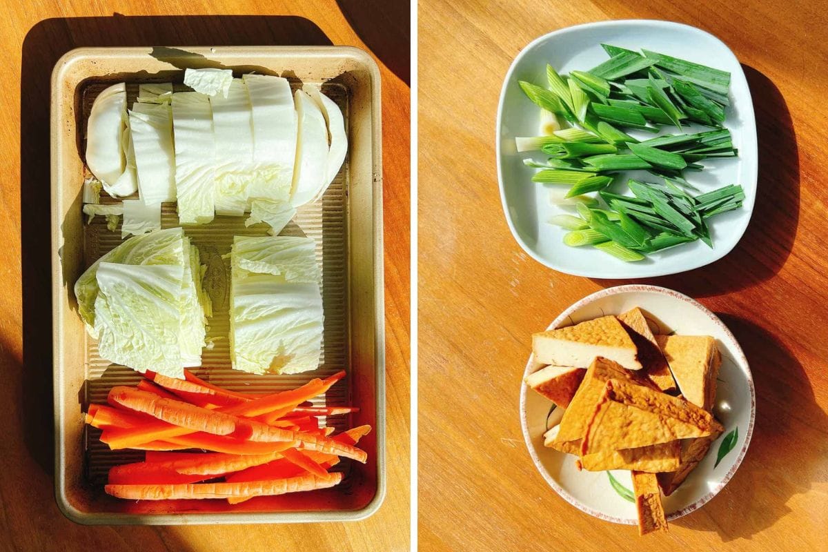 A tray with napa cabbage and carrot sticks on the left; on the right, a plate with chopped green onions and a bowl of sliced tofu—perfect ingredients for a chicken meatball hot pot—arranged on a wooden surface in bright sunlight.