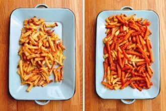 Two metal trays on a wooden surface, each holding crinkle-cut French fries. The left tray has potato fries, while the right tray features sweet potato fries. Both fries are oven baked to crispy.