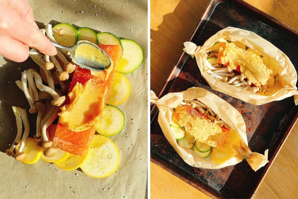 A hand spreads creamy miso butter over salmon on parchment paper. Next to it, two parchment-wrapped miso butter salmon parcels are placed on a baking tray.