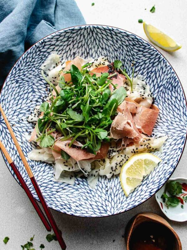a large blue and white salad bowl filled with shaved daikon ribbons, prosciutto, watercress, and lemon dressing. A cool and refreshing daikon salad perfect for summer days.