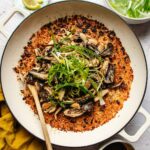 A wide pan filled with miso mushroom crispy rice, topped with sautéed mushrooms and shredded green onions.