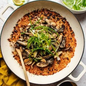 A wide pan filled with miso mushroom crispy rice, topped with sautéed mushrooms and shredded green onions.